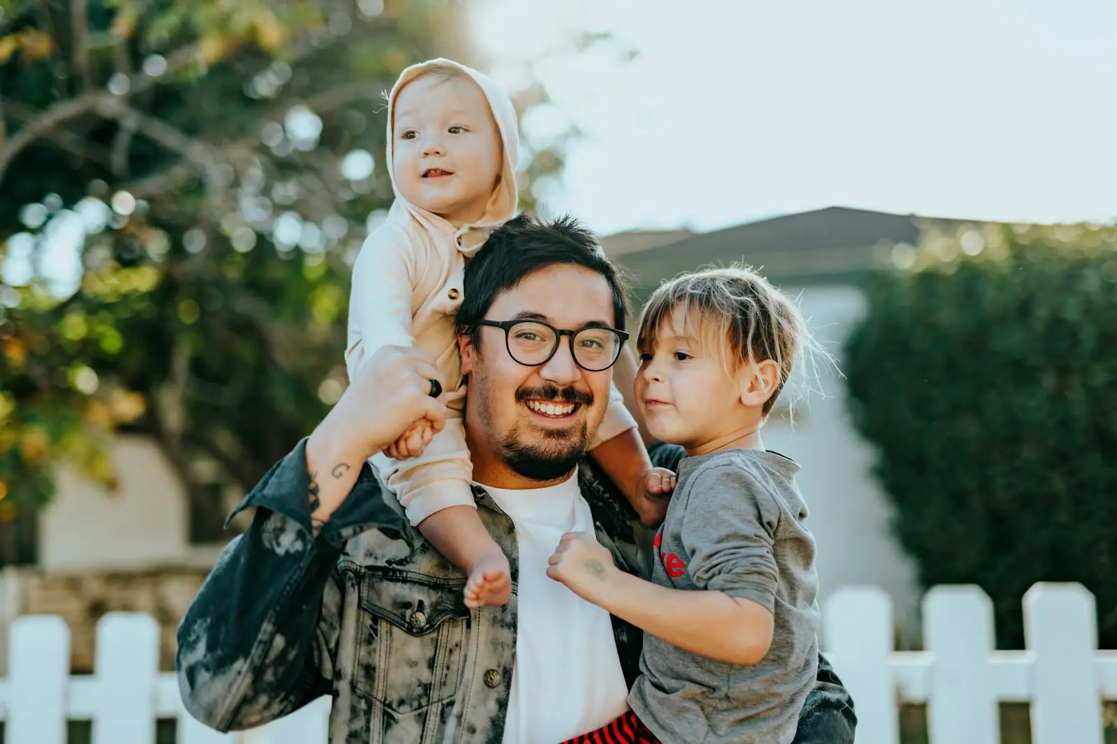 A father and his two children outside their family home at golden hour